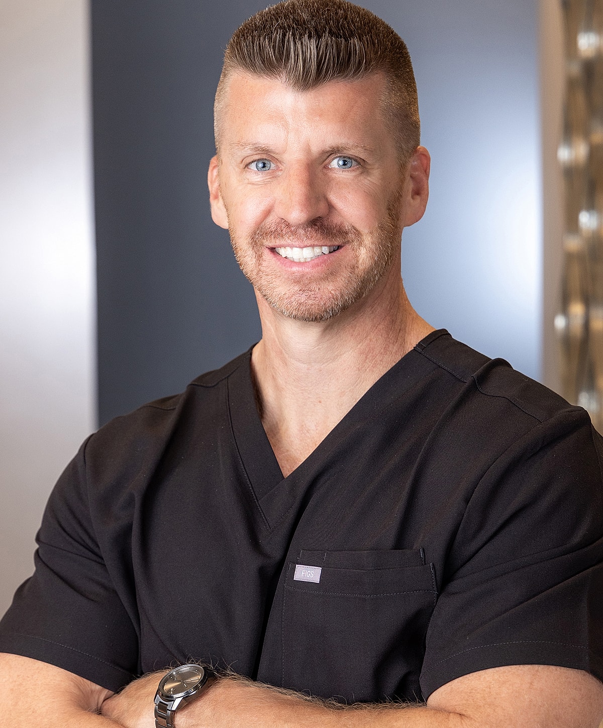 Smiling healthcare professional in black scrubs.