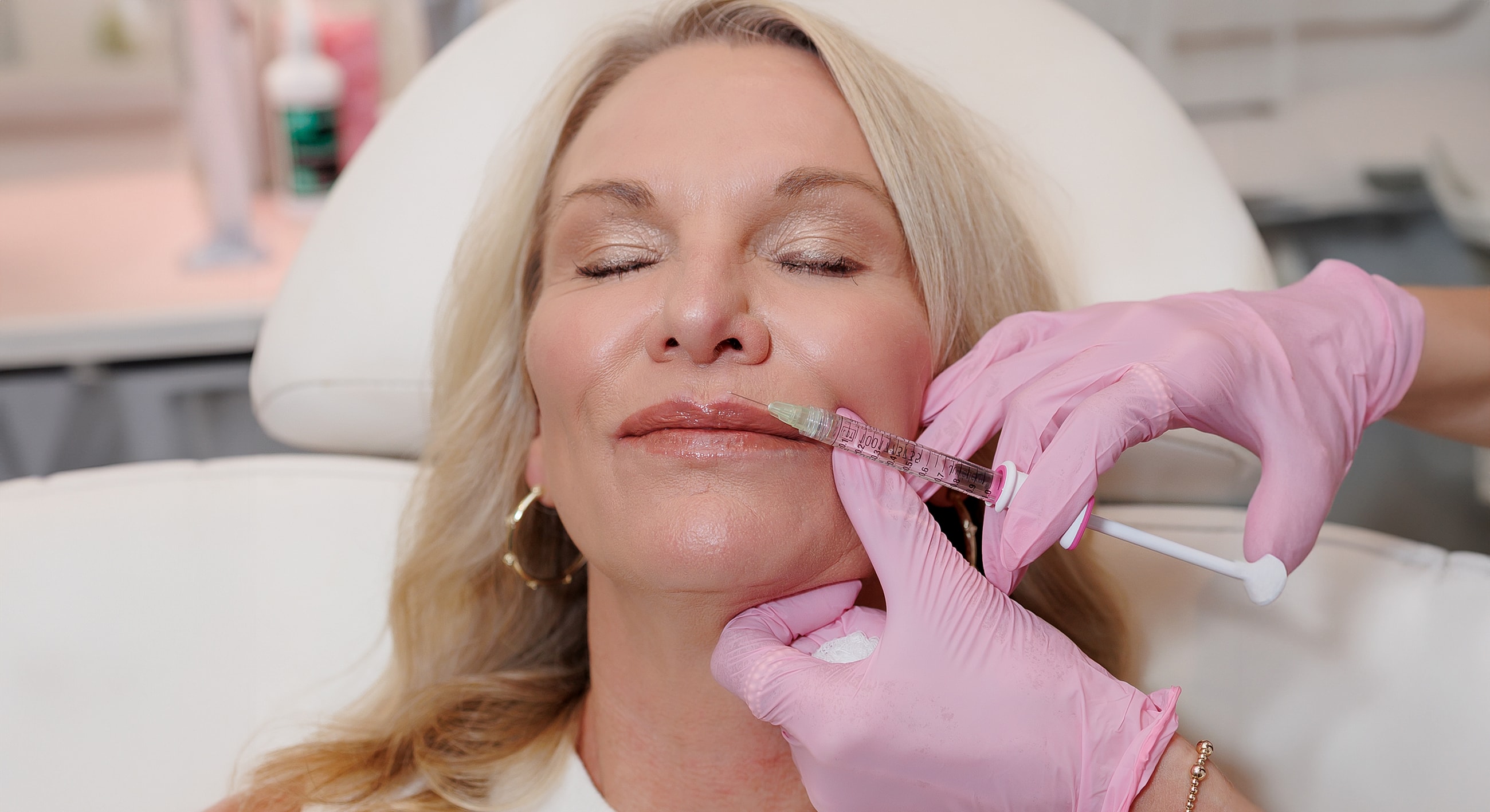 Woman receiving lip filler treatment in clinic.